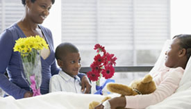 Family visits patient in hospital bed.