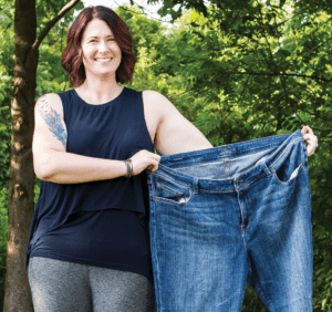 Woman holding up pair of large jeans.