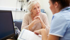 Patient listens intently as medical professional reads information from a form.